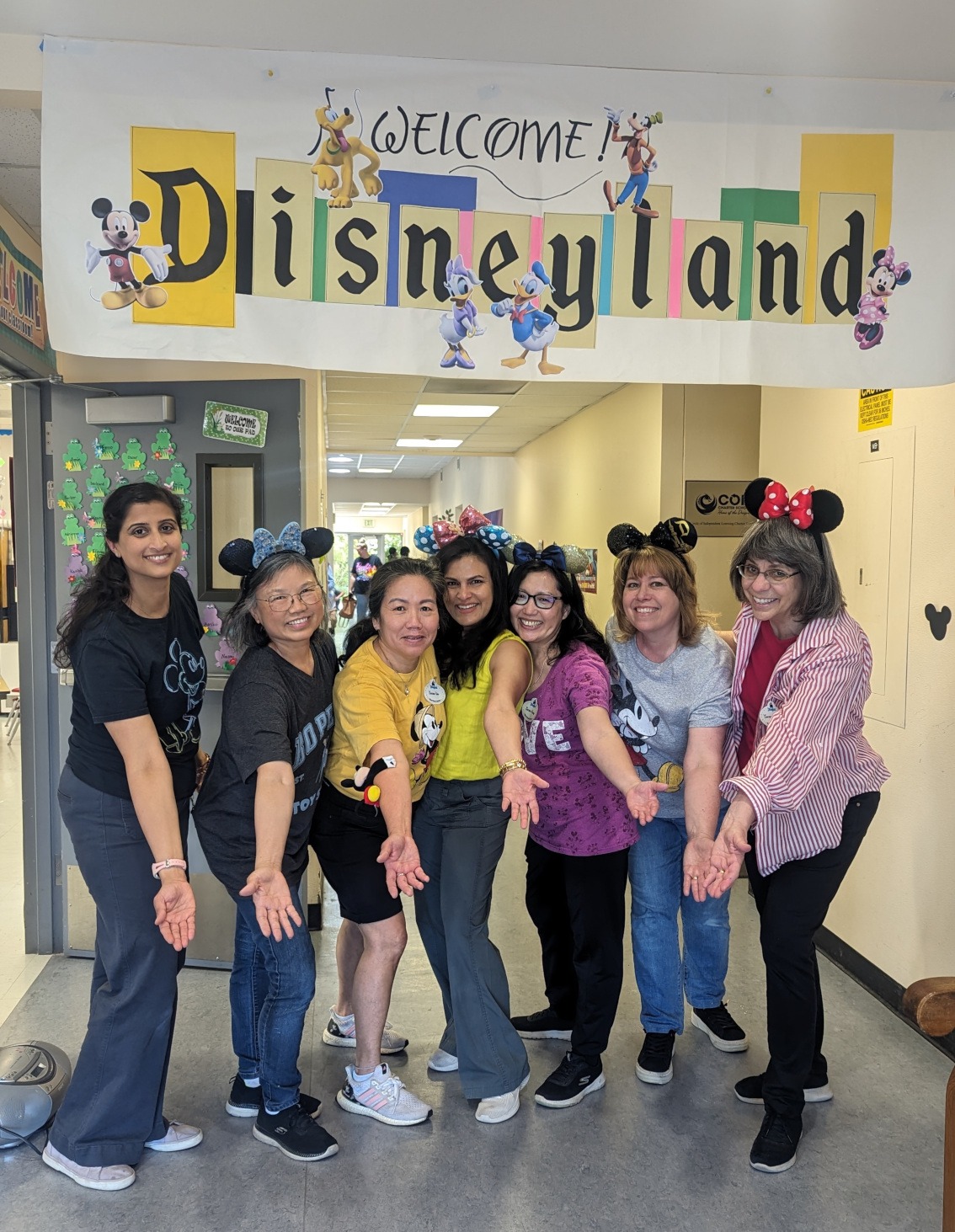 Parent Education staff members standing in front of a sign which reads, "Welcome! Disneyland"